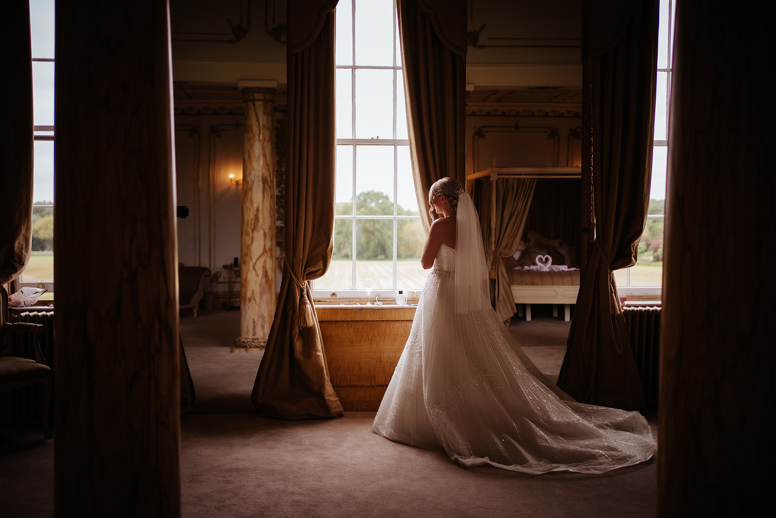 Bride lokking out of the rococco bridal suite at Gosfield Hall