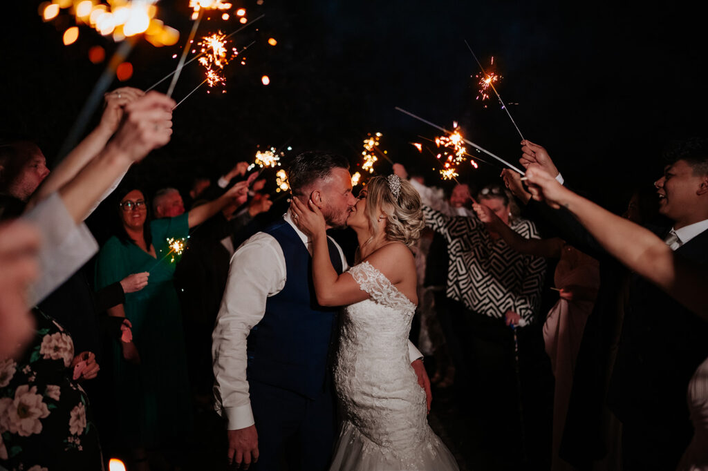 Bride and groom kissing with sparklers at their Essex wedding venue