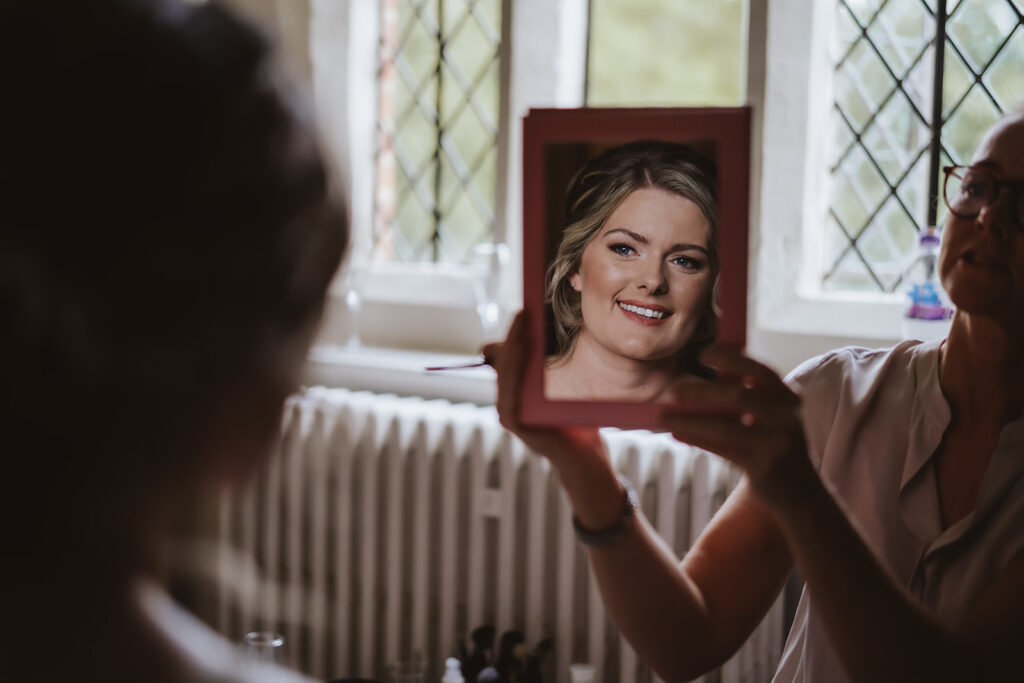 bride looking at herself in the mirror at leez priory wedding venue in essex