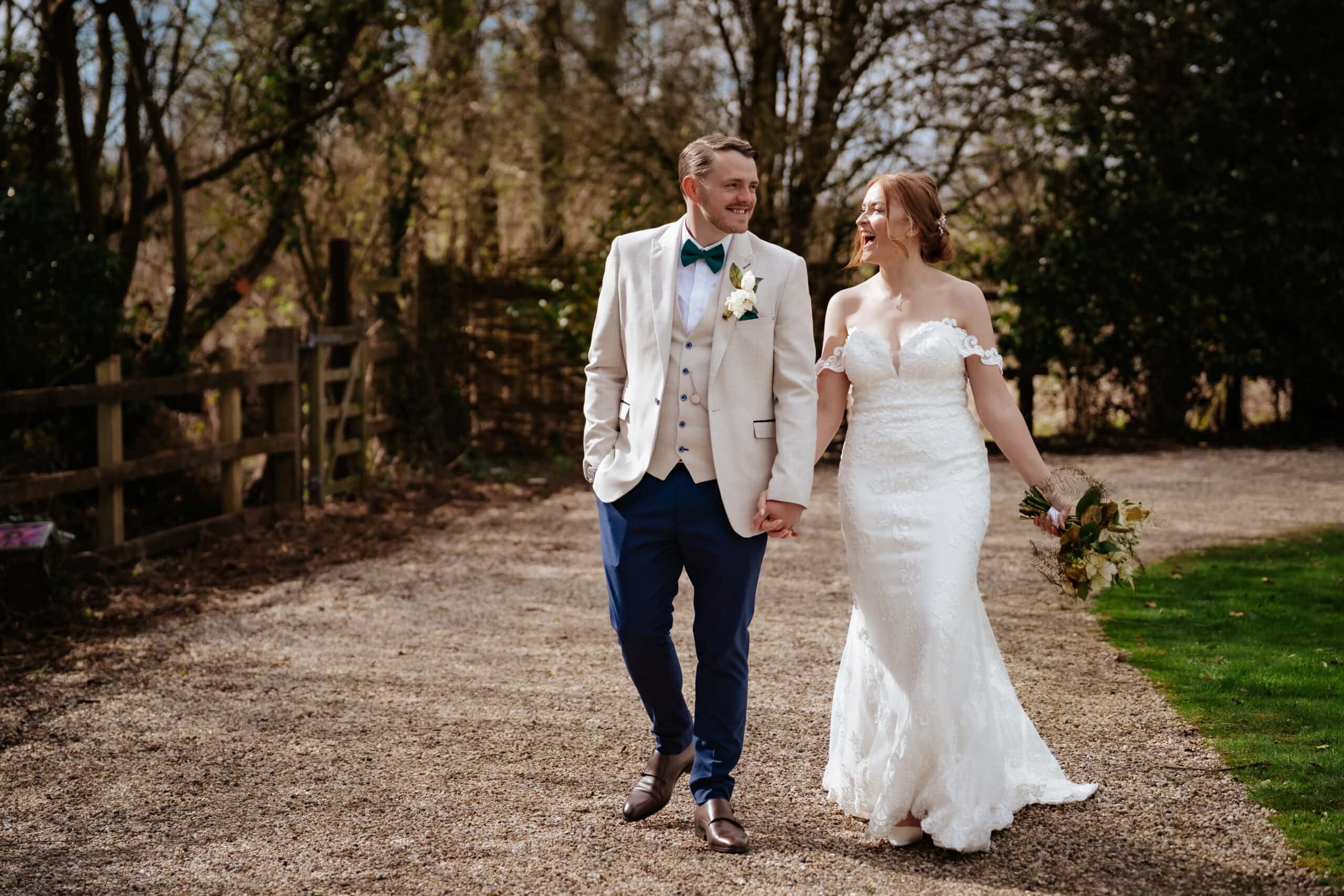 Married couple share an authentic wedding photography moment whilst walking & laughing at Tewin bury farm wedding venue in Hertfordshire