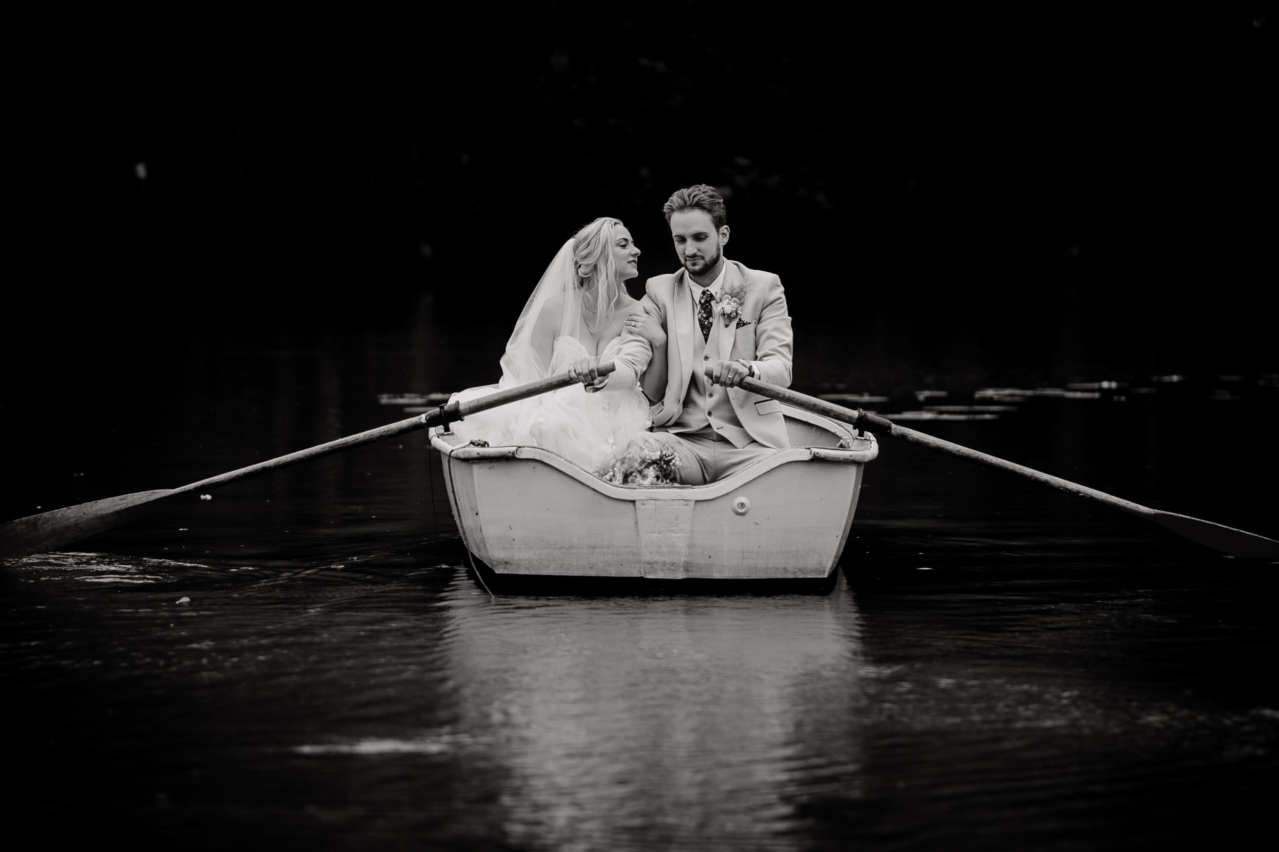 Bride and Groom rowing a boat at their Essex wedding. Essex wedding photographer.