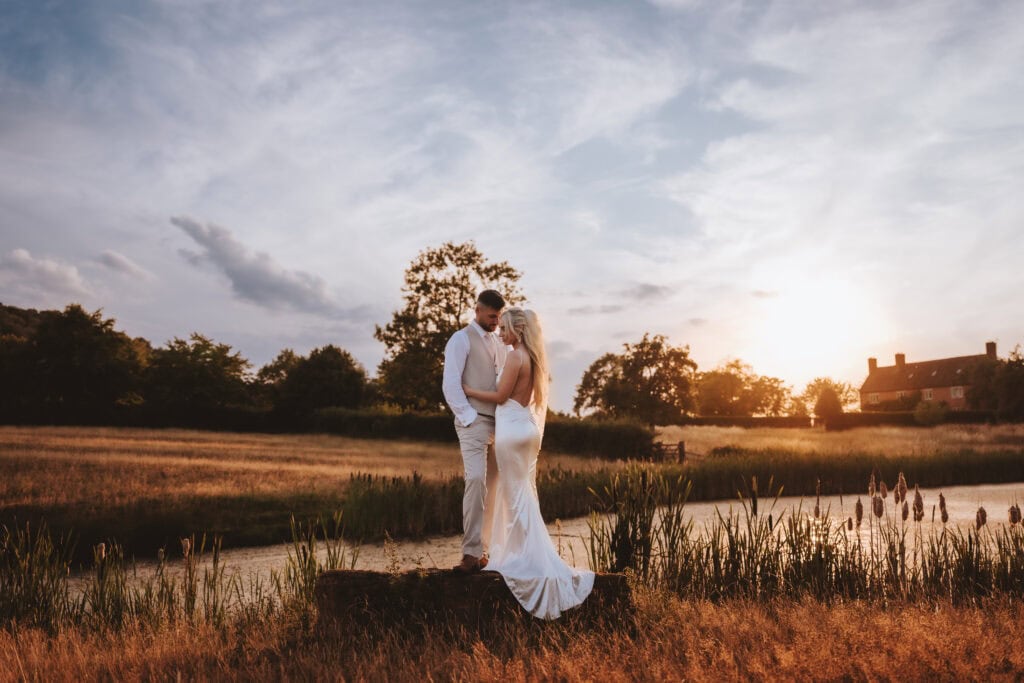 Bride and groom embracing at golden hour in the fields at Primrose Hill Farm, Cotswolds - Danielle and Jordan's summer wedding photographed by Lily & White