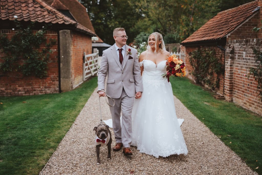 Holly and Billy share a quiet walk with their dog Otis on their wedding day at Blake Hall, Ongar, October 2025 – wedding photography by Tel, Lily & White